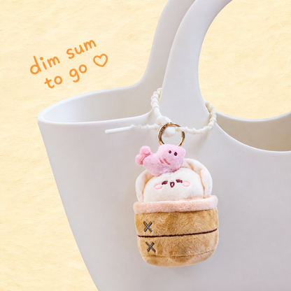 KUKI tan BBQ pork bun plush gel pen keychain hanging from a white handbag